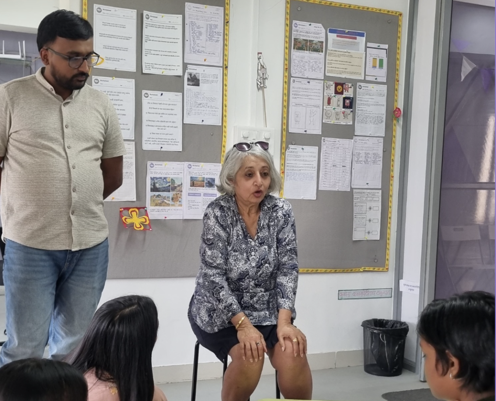A woman is seated and addressing a small group.